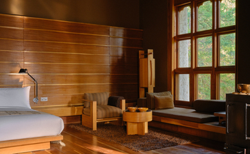 Thimphu suite interior with warm wooden walls, decorative vessels, and window overlooking Bhutan landscape.