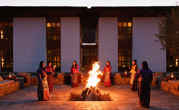 Guests gather around a fire pit on the terrace at Aman's Bumthang lodge in Bhutan as evening falls.