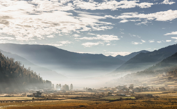 Gangtey Lodge valley view with mist-covered mountains and golden meadows in Bhutan.