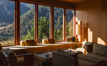 Mo Chhu Suite at Amankora Punakha with wooden desk overlooking mountain valley through floor-to-ceiling windows.