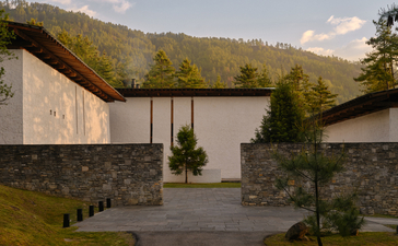Amankora Thimphu lodge exterior with stone walls and mountain backdrop.