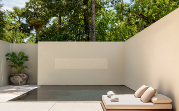 Pool Suite pool at Amansara, with loungers beside calm water and lush greenery beyond white walls.