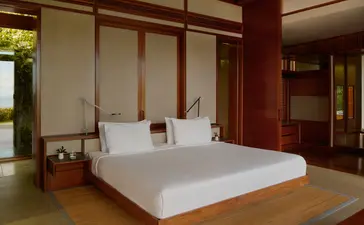 Spacious bedroom at Amanera with platform bed, wooden panelling and warm lighting.