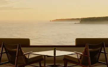 Two wooden chairs facing the sea at sunrise, Amanera resort, Dominican Republic.