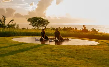 Couple relaxing on expansive green lawn at Amanera resort at sunset.
