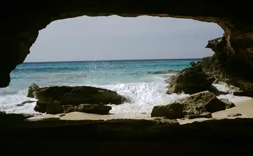 Turquoise waters and white sand beach viewed through a natural rock archway at Amanyara, Turks and Caicos.