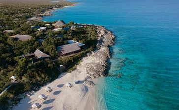 Aerial view of Amanyara's clifftop resort overlooking turquoise waters and white sand beach in Turks and Caicos.