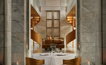 Formal private dining room at Amanzoe with marble columns, a central table set for two, and warm candlelit ambiance.
