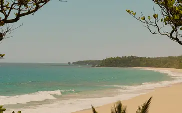 Turquoise waters and sandy beach framed by tropical vegetation at Amanera resort.