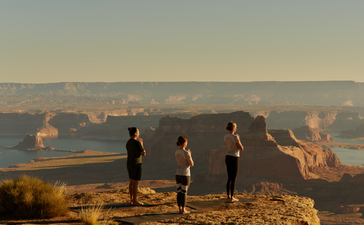 Guests practising yoga at sunrise on a rocky outcrop overlooking Tower Butte at Amangiri.