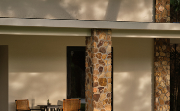Amansara suite exterior with wooden columns, modern architecture and shaded seating area.