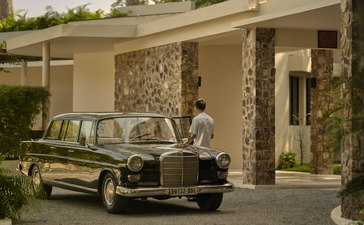 Amansara reception area with vintage car parked beneath stone-clad portico and lush greenery.