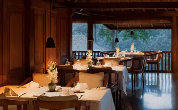 Amandari restaurant terrace at dusk, with warm-lit dining tables overlooking the Ubud valley in Bali.