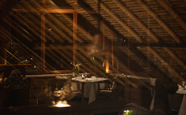 Upper dining venue at Amandari with wooden ceiling and warm candlelit tables overlooking Ubud.