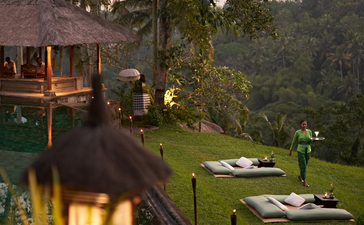 Sundowner gathering on Amandari's lawn at dusk, with warm lighting and guests seated amongst the grounds.