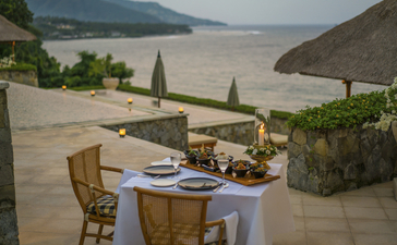 Rijsttafel dinner setup by the pool at Amankila resort, Bali, with views across the landscape.