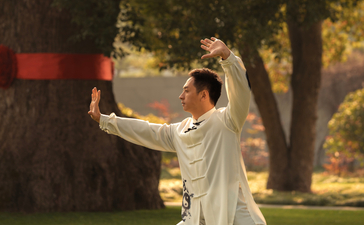 Woman in white shirt practising tai chi on a lawn at Amanyangyun, China, at dusk.