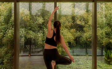 Yoga instructor in a standing pose within the Pilates and yoga studio at Amanyangyun, Shanghai, with garden views through large windows.