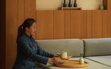 Spa therapist at Amanyangyun Shanghai preparing for a treatment session in a serene wooden-panelled room.