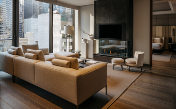 Salotto con divano beige, camino e vista su New York presso Aman New York.
