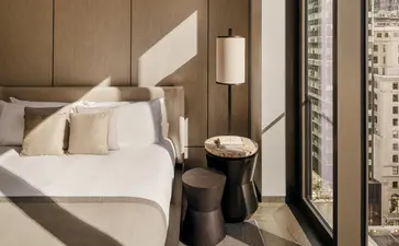 Principal bedroom at Aman New York with neutral bedding and soft natural light from window.