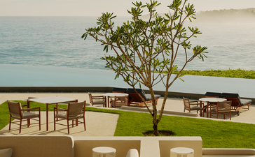 Terrasse extérieure du bar d'Amanera avec vue sur la mer des Caraïbes, tables en bois et verdure côtière en République dominicaine.