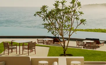 Exterior bar at Amanera resort overlooking the Dominican coast with dining tables beneath a solitary tree and ocean view.