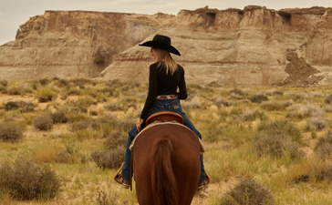 Rider on horseback across Utah desert landscape at Amangiri, summer.