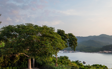 Amanoi accommodation pavilion with dining area overlooking forested coastline and bay in Vietnam.