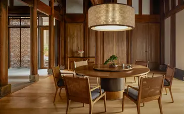 Dining area at Amanyangyun with round table, wooden chairs, and pendant lighting in warm earth tones.