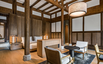 Guest bedroom at Amanyangyun featuring wooden architectural details, seated seating area, and neutral tones.