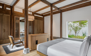 Principal bedroom at Amanyangyun with four-poster bed, wooden ceiling beams, and garden views.