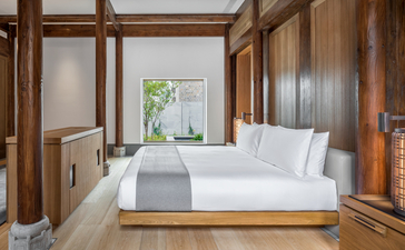Principal bedroom with wooden four-poster bed at Amanyangyun villa, featuring floor-to-ceiling windows overlooking gardens.