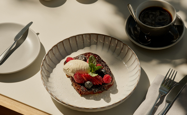 Breakfast at Amanyara with plated fruit dish, coffee cups, and cutlery on white linen.