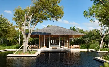 Beachfront sala pavilion with wooden architecture reflected in still water at Amanyara resort, Turks and Caicos.