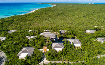 Five-bedroom beach sala villa at Amanyara, Turks and Caicos, surrounded by tropical vegetation and turquoise waters.