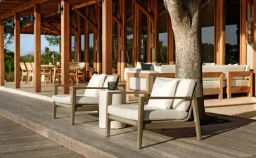 Sala de playa con cinco dormitorios en Amanyara resort, Turks y Caicos, con sillas de madera y vistas al mar.
