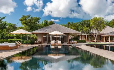 Villa com cinco quartos em Amanyara, resort em Turks e Caicos, com piscina refletiva e paviliões ao redor.