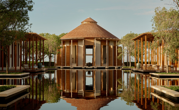 Amanyara resort pavilion reflected in still water, surrounded by mangroves at dusk.
