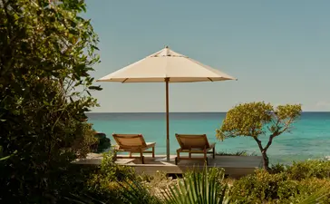 Cream parasol and loungers on the sandy beach at Amanyara, overlooking turquoise waters.