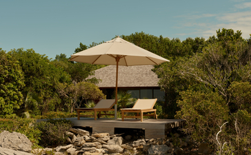 Ocean cove pavilion at Amanyara with shaded seating overlooking turquoise waters and tropical vegetation.