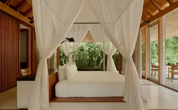 Pavilhão de piscina em Amanyara, resort em Turks e Caicos, com cama de dossel branco e vistas para a natureza.