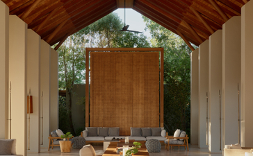 Pavillon d'arrivée à Amanyara, avec plafond en bois et bancs en pierre encadrant un autel central.