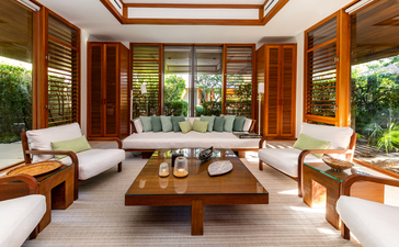 Six-bedroom villa living area at Amanyara, Turks and Caicos, with wooden furnishings and garden views.
