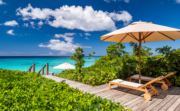 アマンヤラ・リゾートのビーチサラ・ヴィラから、ターコイズブルーの海を見渡す木製デッキとイエローパラソル。