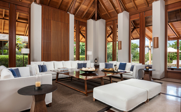 アマンヤラ・リゾートの6ベッドルーム・ビーチ・サラ・ヴィラのオープンな居間空間。木製の柱と高い天井が特徴で、モダンな家具と海の眺めが配置されている。