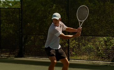 Joueur de tennis en position de service sur un court à Amanyara, resort aux Turks-et-Caïques.