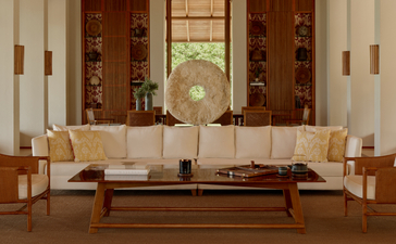 The Artists Villa living room at Amanyara, featuring a neutral seating arrangement with a wooden coffee table and decorative fan.