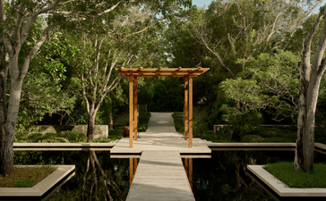 Wooden pergola structure framing a reflecting pool at Amanyara, surrounded by tropical vegetation.