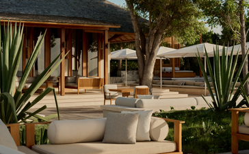 Artist's Villa at Amanyara with outdoor seating area surrounded by tropical plants and wooden architecture.